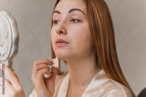 Woman applying foundation and concealer makeup. Do it yourself makeup for problem skin 