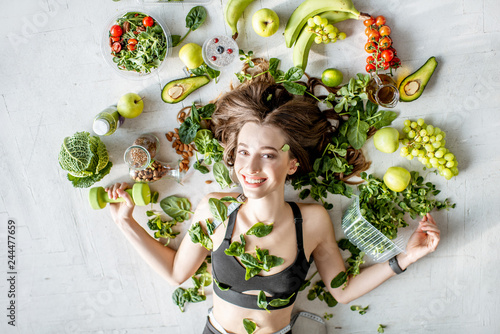 Beauty portrait of a sports woman surrounded by various healthy food lying on the floor. Healthy eating and sports lifestyle concept