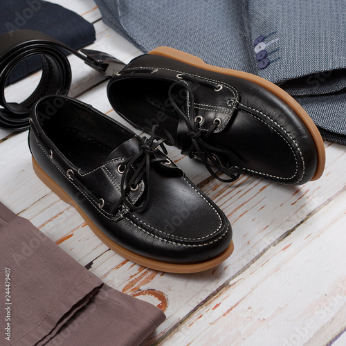 male loafers, belt and clothes on wooden background