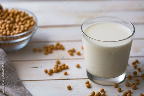 Raw soy seeds and glass of milk on slate background. Organic farming