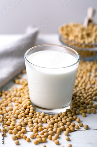 Raw soy seeds and glass of milk on slate background. Organic farming