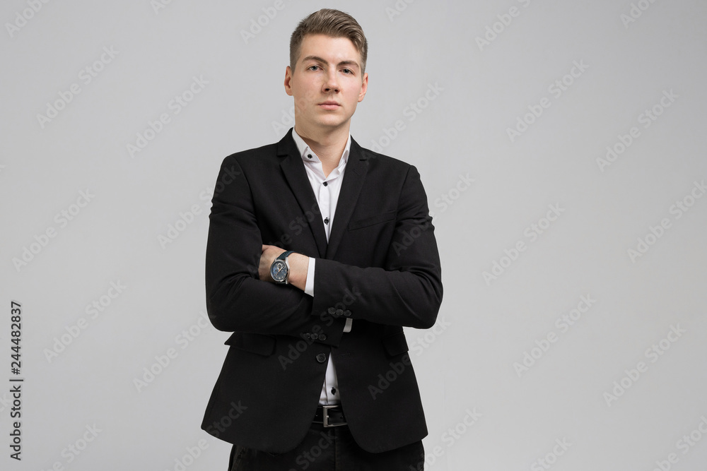 Portrait of young man in black suit with arms crossed isolated on white background Portrait of young man in black suit with arms crossed isolated on white background
