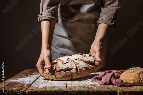 Fototapete Baker or chef holding fresh made bread