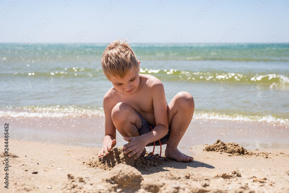 Happy child playing with sand at the beach in summer Happy child playing with sand at the beach in summer