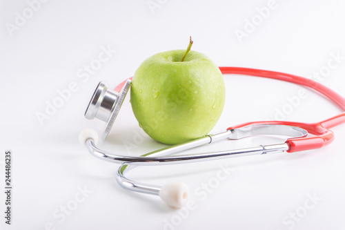 Green Apple with medical stethoscope isolated on white background for healthy eating. Selective focus and crop fragment. Healthy and copy space concept photo