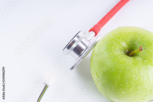 Green Apple with medical stethoscope isolated on white background for healthy eating. Selective focus and crop fragment. Healthy and copy space concept photo