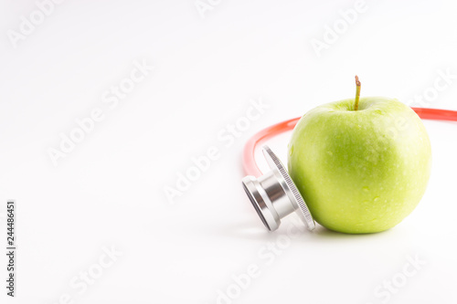 Green Apple with medical stethoscope isolated on white background for healthy eating. Selective focus and crop fragment. Healthy and copy space concept photo