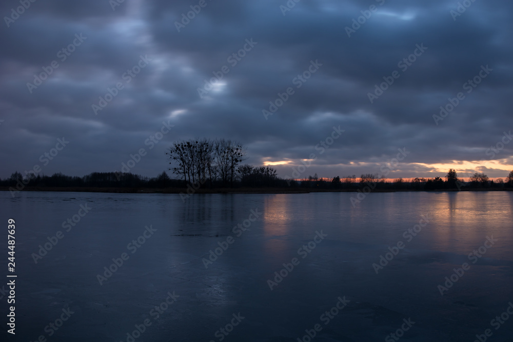 Cloudy sky after sunset, over a calm lake