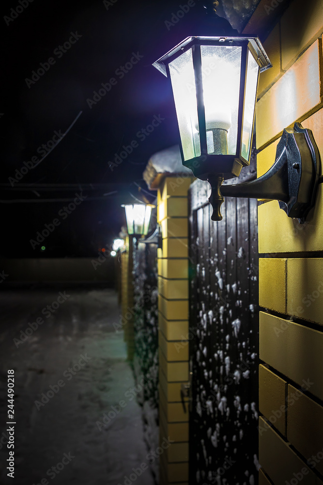 Old style street lamp with falling snow at night