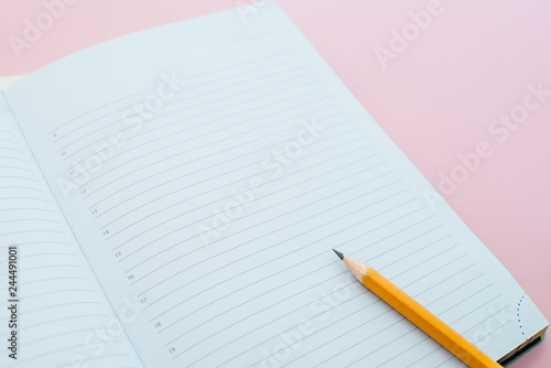 A pencil on a notebook in the linel. School supplies. White sketch book with orange pencil. Note book and pencil photo