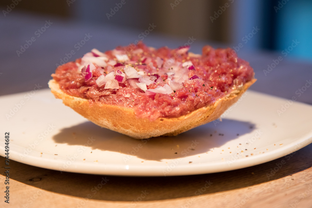 Teller Beef Tatar Mettbrötchen mit Rindfleisch und Zwiebeln auf Holz Tisch Teller Beef Tatar Mettbrötchen mit Rindfleisch und Zwiebeln auf Holz Tisch