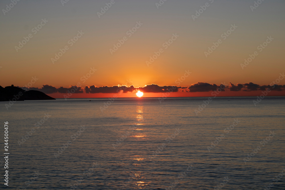 Beautiful morning sunrise over the sea showing yellow sun with a few clouds in the background, taken in Spain Costa Brava near Alicante and Benidorm Beautiful morning sunrise over the sea showing yellow sun with a few clouds in the background, taken in Spain Costa Brava near Alicante and Benidorm