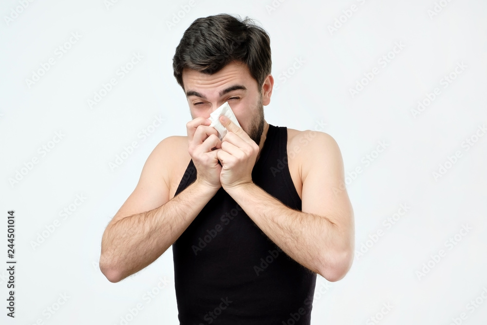 Hispanic young man with black beard being ill sneezing. Hispanic young man with black beard being ill sneezing.