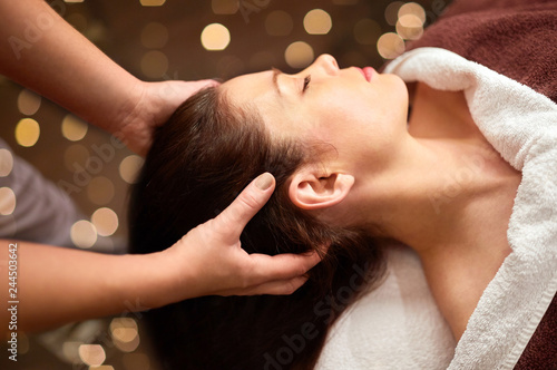 people, beauty, lifestyle and relaxation concept - beautiful young woman lying with closed eyes and having head massage at spa photo