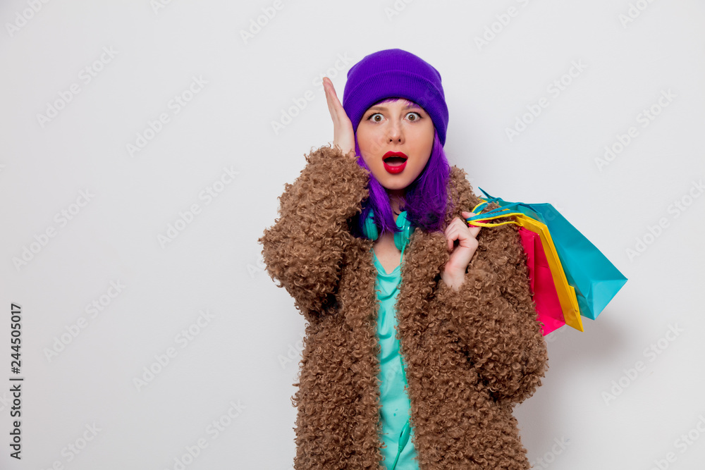 Φωτογραφία Beautiful young girl with purple hair in jacket holding shopping bags on white background