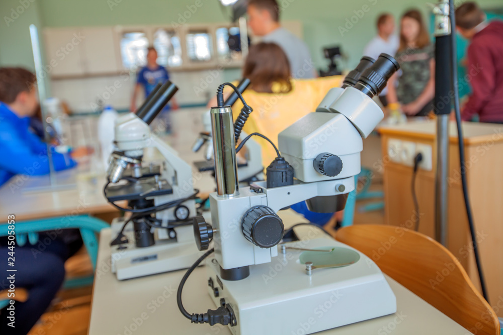The biology classroom. There are microscopes on the table.