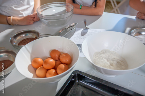 Students are waiting to start baking. They're having a cooking class. There are eggs and four on the table.