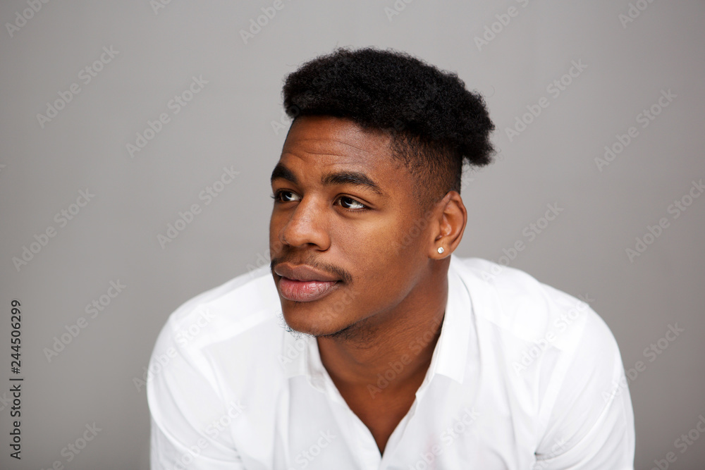 Close up young black man looking away against gray background Close up young black man looking away against gray background