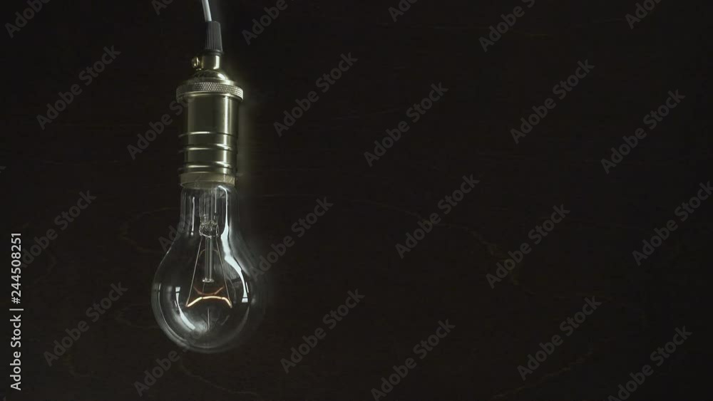 The light bulb slowly lights up, quickly flickers on a background from a wood The light bulb slowly lights up, quickly flickers on a background from a wood