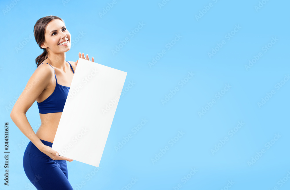 Woman in fitnesswear showing signboard, over blue Woman in fitnesswear showing signboard, over blue