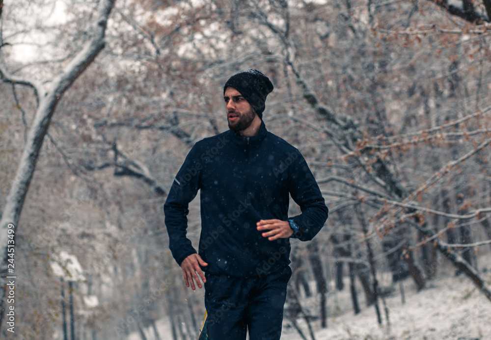 Young man running in city park at cold winter day. Young man running in city park at cold winter day.