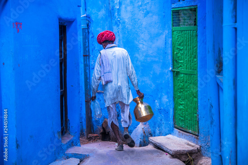 Man wearing traditional clothing walking in blue street, Bundi, India photo