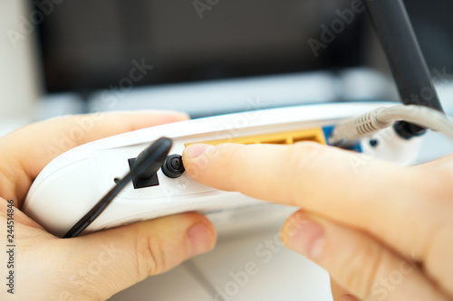 Man pressing power button on the wifi router. photo