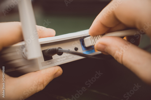 Obraz na płótnie Man plugging internet cable into wifi router.