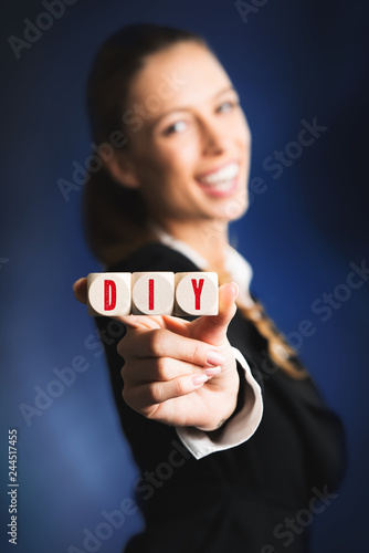businesswoman is holding cubes with acronym DIY for "do it yourself"