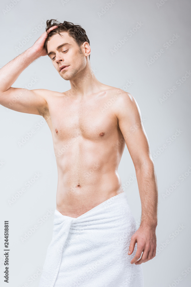 handsome shirtless macho posing in towel isolated on grey