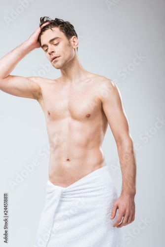 handsome shirtless macho posing in towel isolated on grey