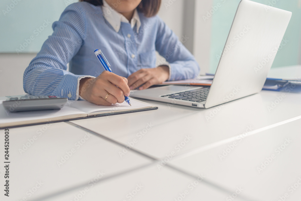 Young businesswoman taking notes in notebook and sitting in the businessroom Young businesswoman taking notes in notebook and sitting in the businessroom