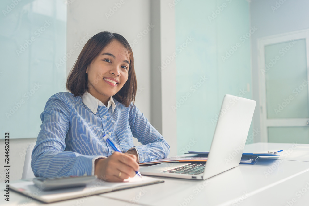 Smiling businesswoman taking notes in notebook and sitting in the businessroom Smiling businesswoman taking notes in notebook and sitting in the businessroom