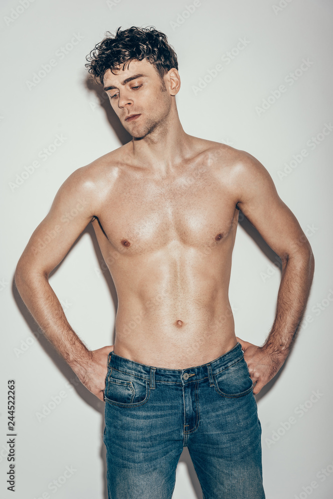 sexy stylish muscular macho in jeans posing on grey