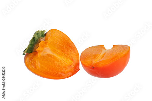 Persimmon fruit or diospyros kaki with green leaves sliced in two halves on white background isolated close up