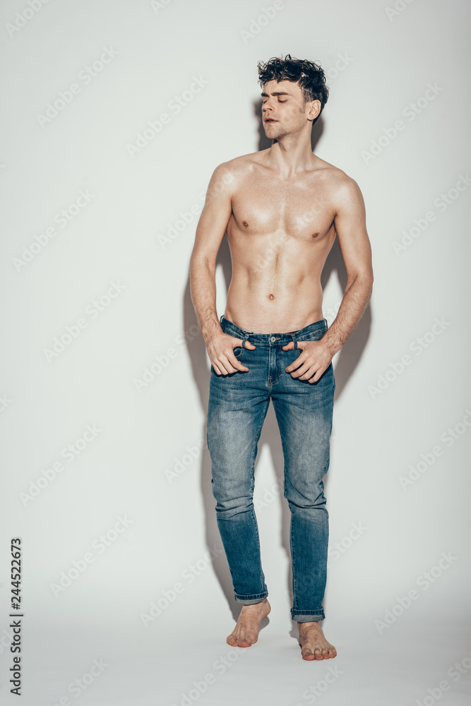 sexy shirtless handsome man in jeans posing on grey
