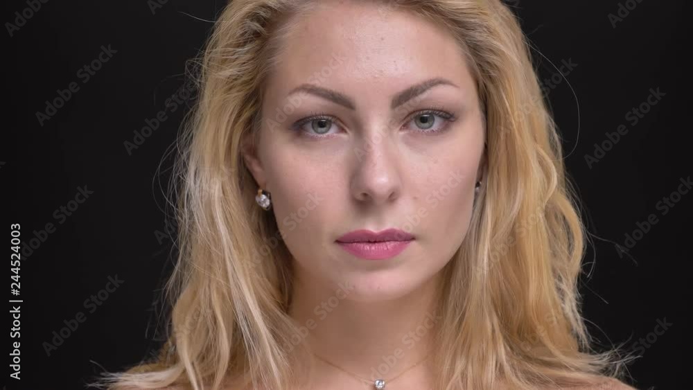 Close-up portrait of gorgeous caucasian long-haired woman watching calmly into camera on black background. Close-up portrait of gorgeous caucasian long-haired woman watching calmly into camera on black background.