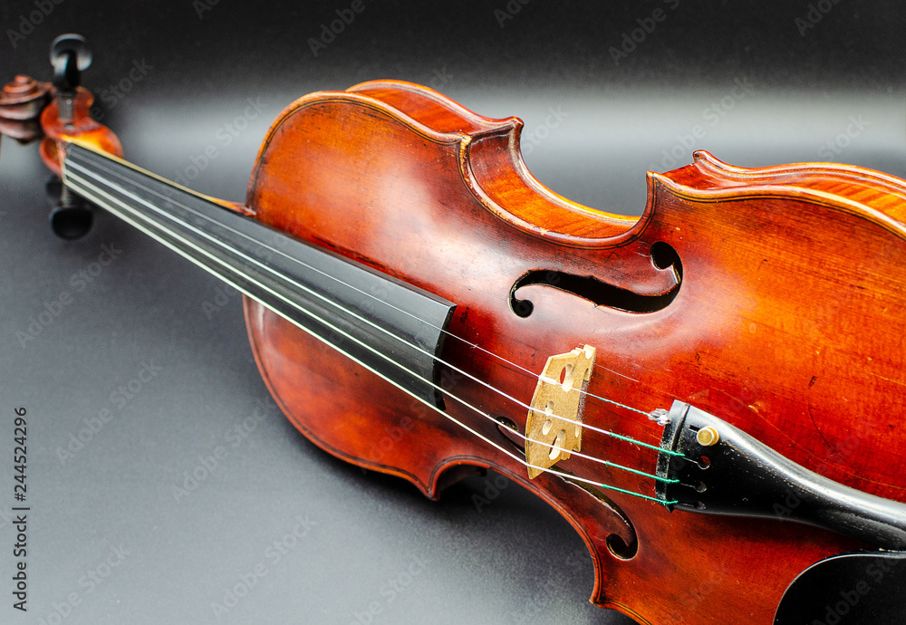 Professional violin in a dynamic position slightly tilted to the side, shot in a studio on a dark background with similar to concert light lighting Professional violin in a dynamic position slightly tilted to the side, shot in a studio on a dark background with similar to concert light lighting