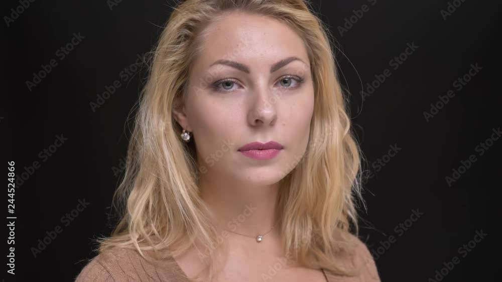 Close-up portrait of gorgeous caucasian long-haired woman turns and watches calmly into camera on black background. Close-up portrait of gorgeous caucasian long-haired woman turns and watches calmly into camera on black background.
