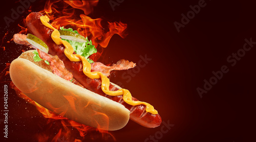 Fotografia hot dog with big sausage and mustard on fire background