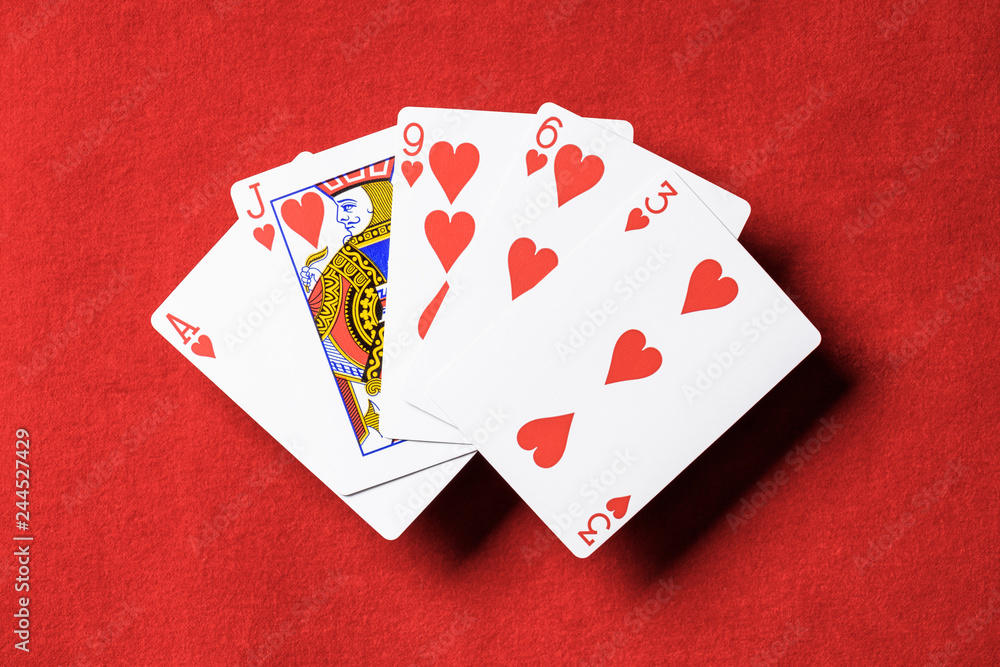 Obraz premium top view of red poker table and unfolded playing cards with hearts suit
