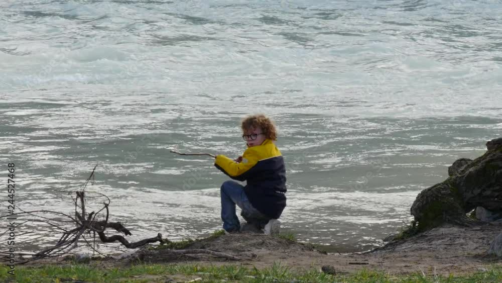 young boy with curly hairs playing near the river at autumn young boy with curly hairs playing near the river at autumn