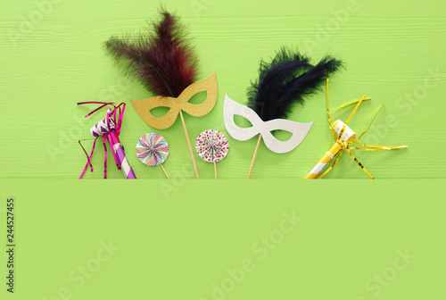 carnival party celebration concept with colorful masks over green wooden background. Top view. Flat lay. photo