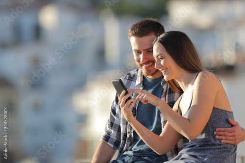 Happy couple browsing phone content in a town outskirts