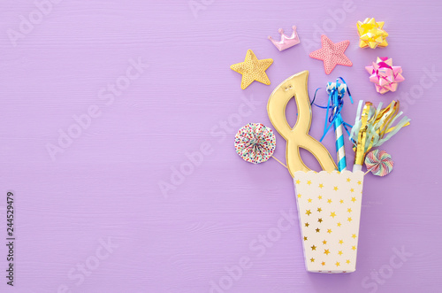 carnival party celebration concept with mask and colorful party accessories over purple wooden background. Top view. Flat lay. © tomertu