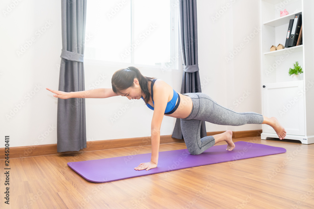 Woman cardio workout or yoga on training mat in living room at home - healthy concept