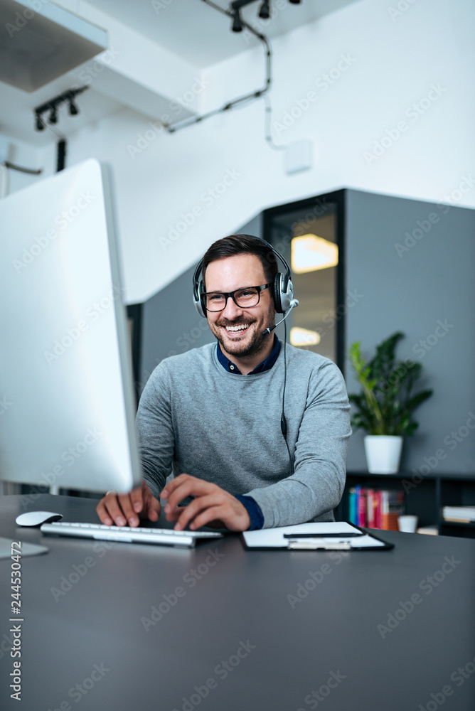 © bnenin - Young business man working on computer with headset.