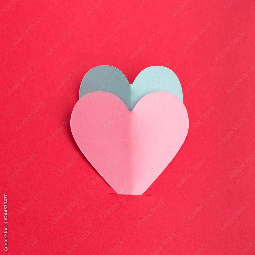 Paper cut of pink and blue hearts on red background. Valentine's Day concept. Flat lay
