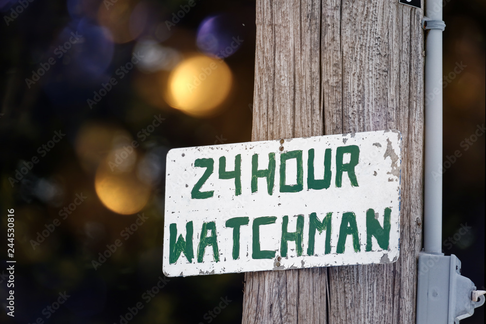 A rustic hand painted sign for a 24 hour watchman. A rustic hand painted sign for a 24 hour watchman.