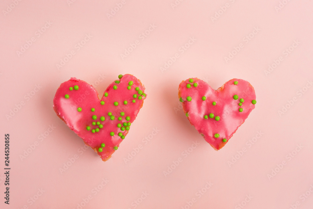 Valentine heart shaped strawberry cakes decorated with green sugar balls on pink background. Flat lay. Top view
